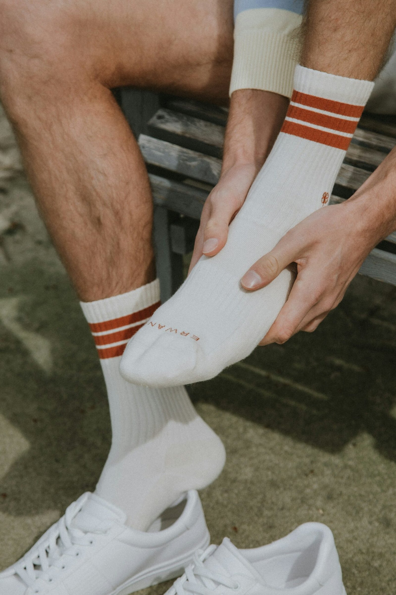 Man putting on white socks with red stripes